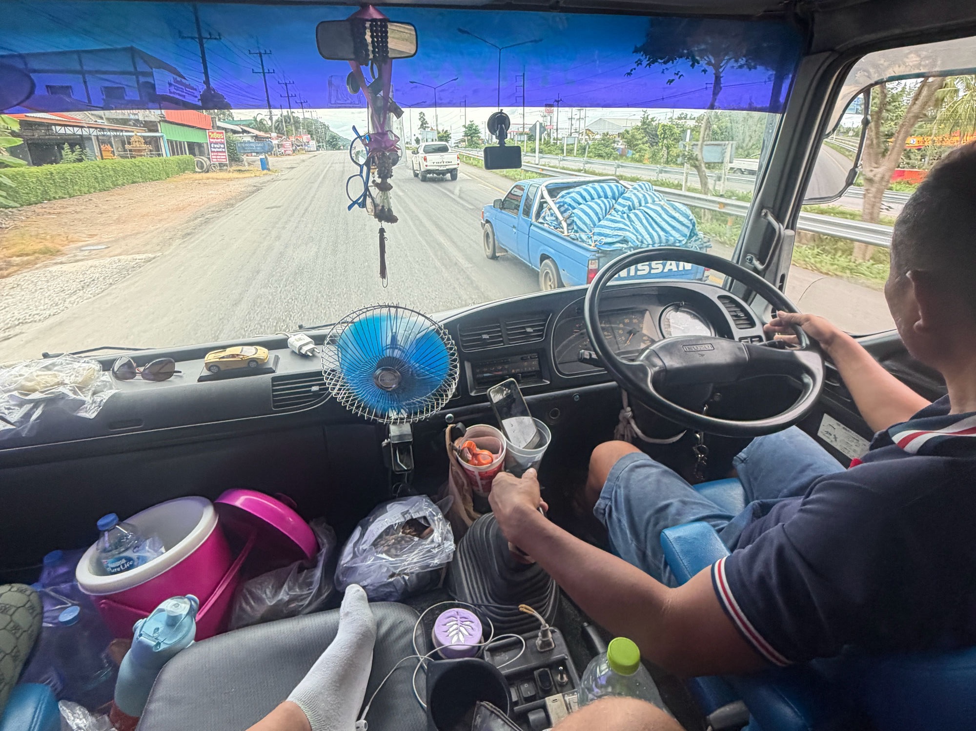 Blick aus der Fahrerkabine des LKW auf dem Weg von Koh Tao nach Bangkok — Straße, Ventilator, vollbepacktes Cockpit