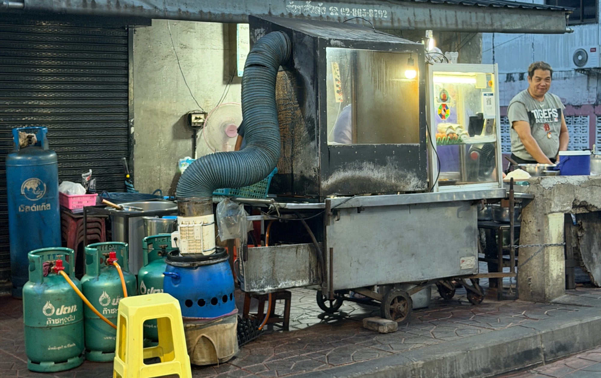 Uncle Tu 10 Bath Streetfood-Stand in Bangkok — Garküche mit Gasflaschen, Abzugsschlauch, kleiner Verkäufer am Wagen