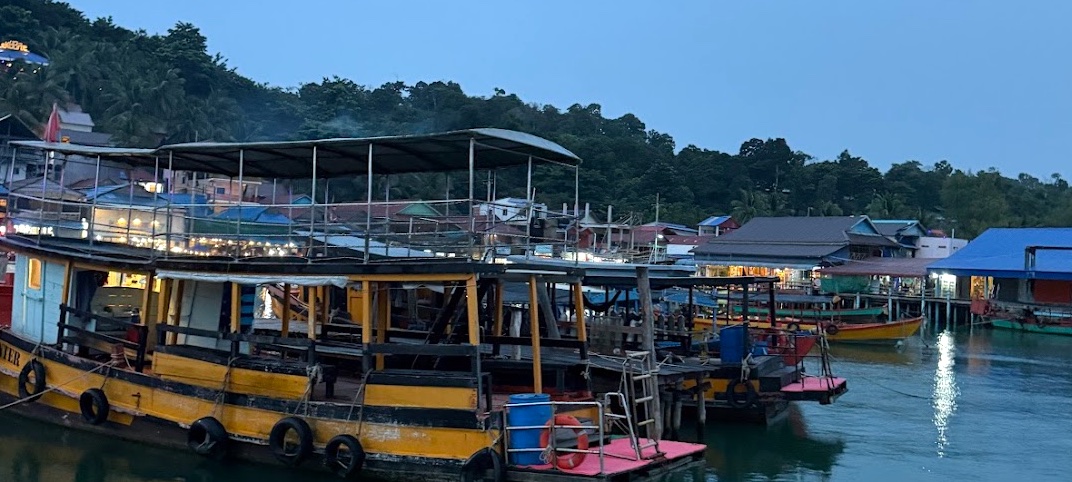 Hafen von Koh Toch auf Koh Rong in der Abenddämmerung, bunte Boote liegen am Pier