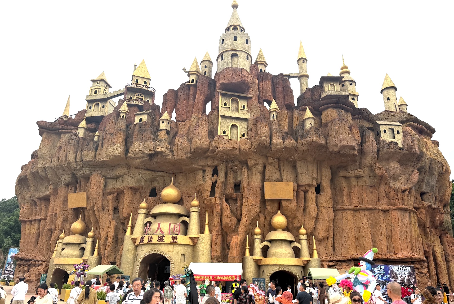 Eingang zum Kingdom of the Little People bei Kunming — Schloss-Attrappe aus Fels mit goldenen Türmchen und chinesischer Beschriftung 小人国 魔法城堡