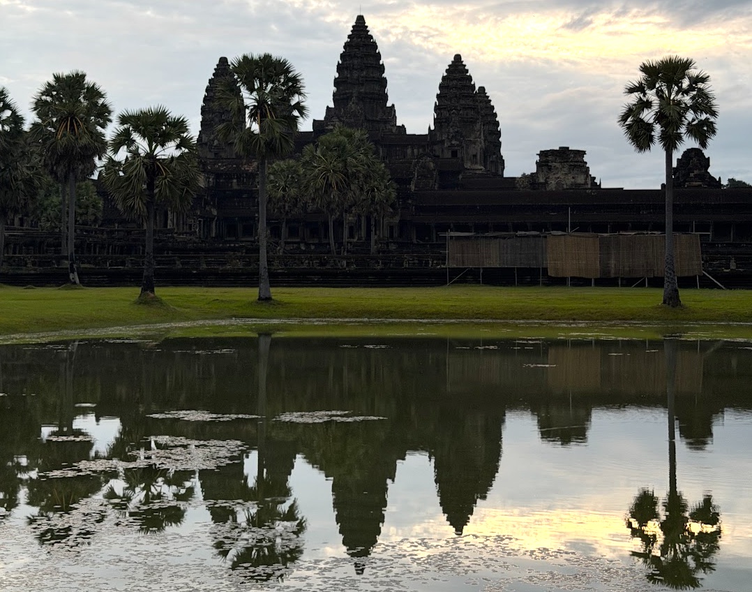 Angkor Wat im Morgenlicht, die Tempeltürme spiegeln sich im stillen Wasser des Teichs