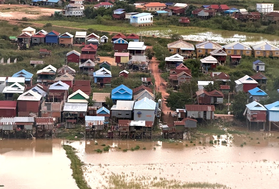 Floating Village bei Siem Reap aus der Vogelperspektive, bunte Stelzenhäuser stehen im Hochwasser des Tonle Sap
